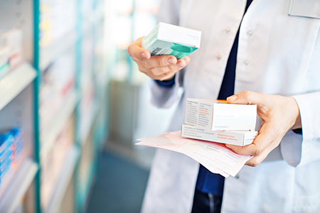 Pharmacist hand closeup with boxes of medications