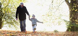 grandpa and grandson walking in the fall leaves in a forest