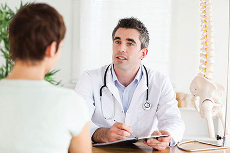 Doctor talking with patient in his office with a spine in the background