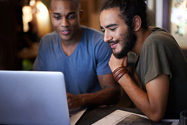 two men using a laptop