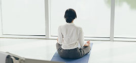 Woman doing yoga in front of wall of windows