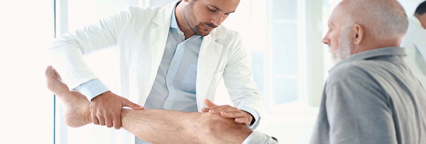Physical therapist examining a man's knee in a clinic
