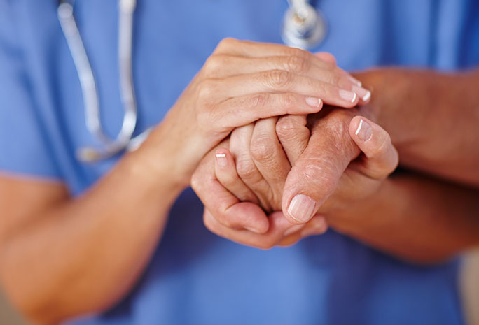 Close up of nurse and patient holding hands