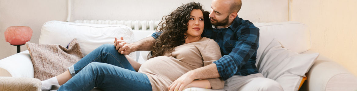 pregnant couple hugging on couch together