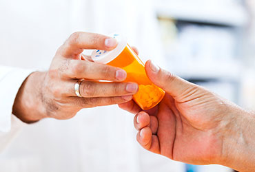 pharmacist handing a bottle of pills to a patient