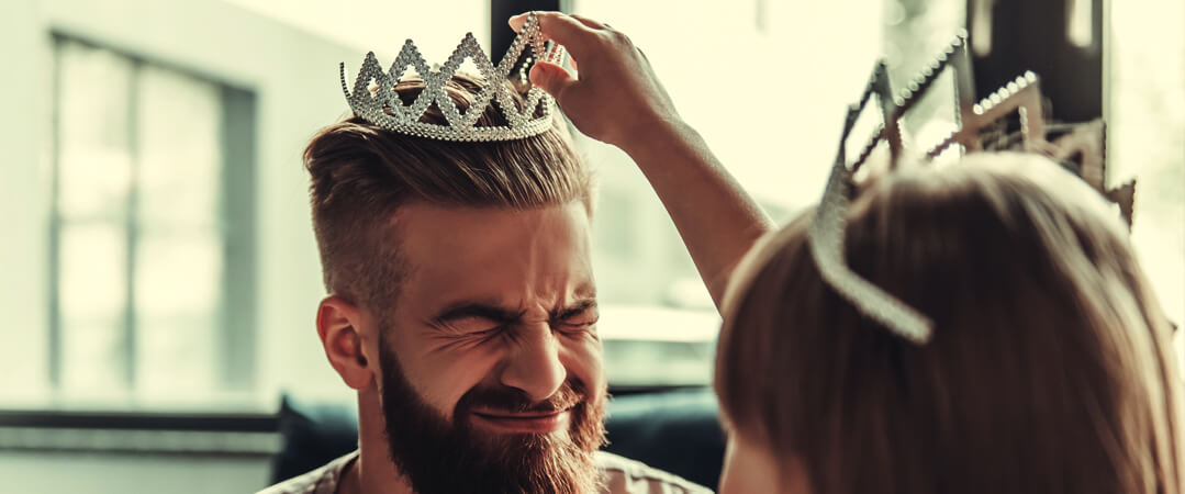 little girl putting crown on her father