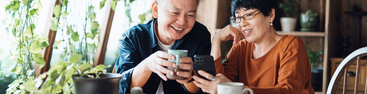 senior couple smiling and looking at mobile phone together