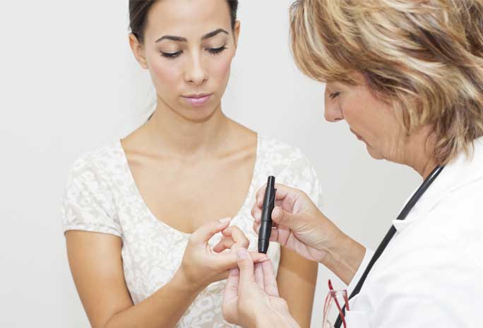 Nurse checking woman's blood sugar